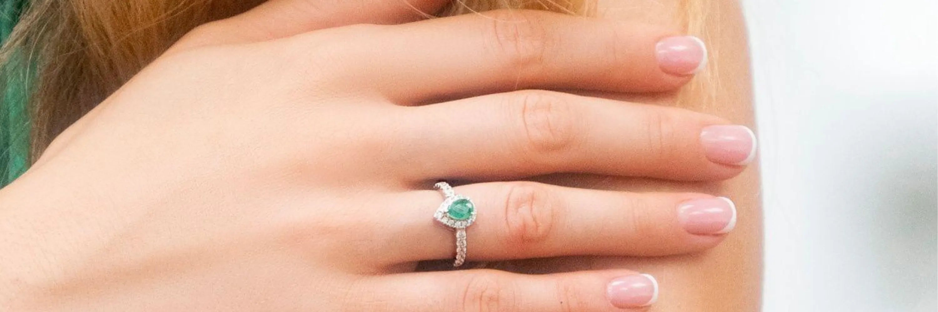 Model wearing Cavell Drop of Passion sterling silver ring featuring a natural emerald gemstone surrounded by cubic zirconia accents with hidden rose quartz gemstone inside the band