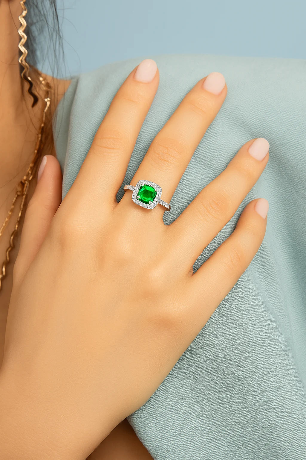 Model wearing Cavell Touch of Luxury natural emerald ring in sterling silver surrounded by round-cut cubic zirconia accents