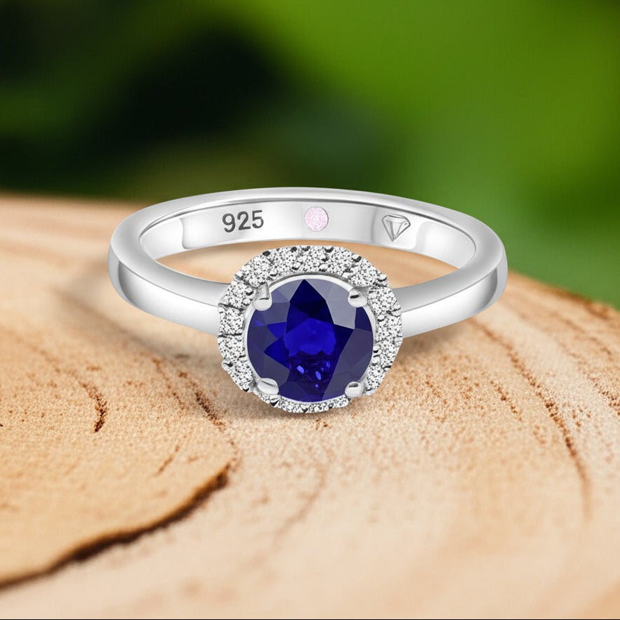 Cavell Eternal Love natural sapphire ring in sterling silver surrounded by round-cut cubic zirconia accents placed on a surface