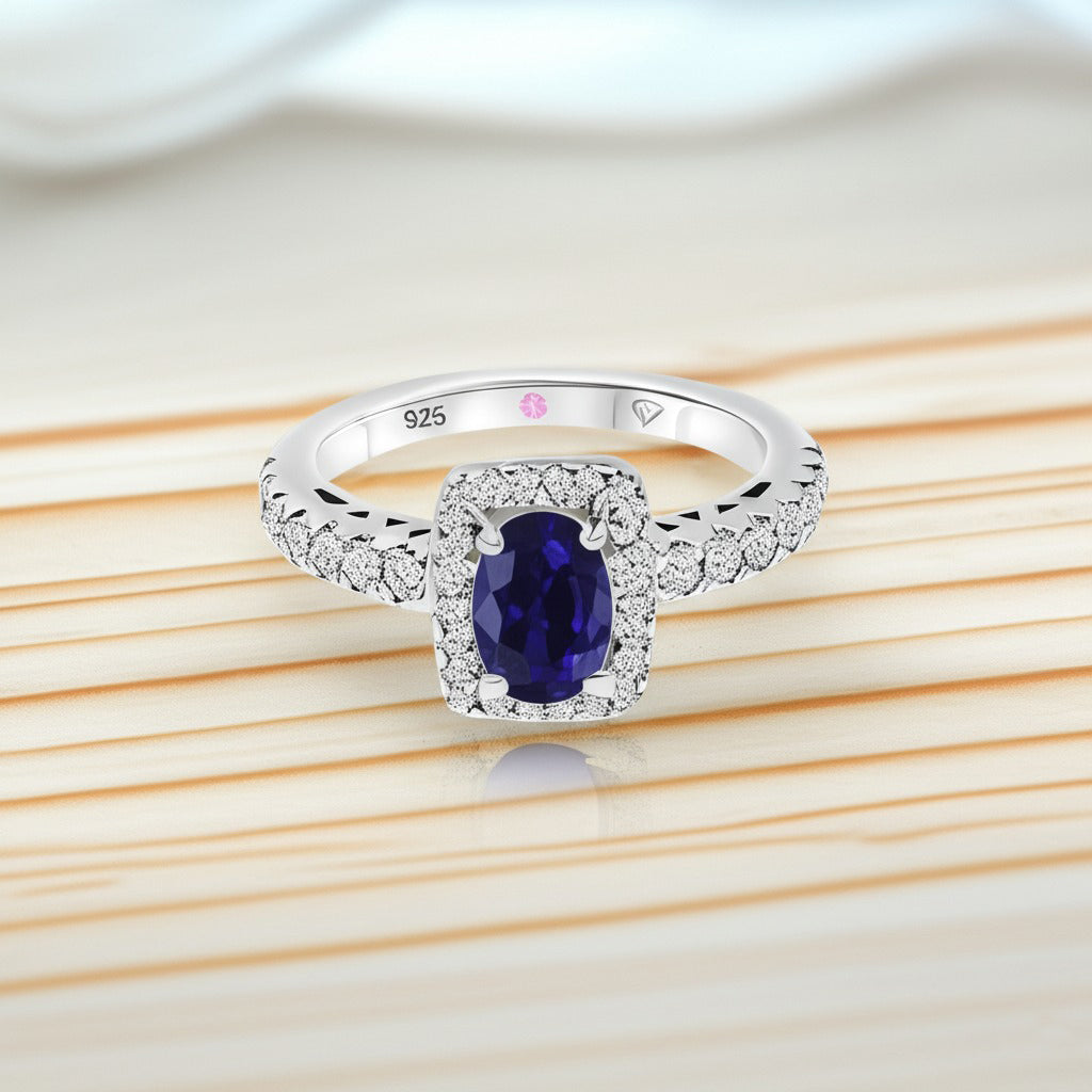 Cavell Feel Timeless natural sapphire ring in sterling silver surrounded by round-cut cubic zirconia accents placed on a surface