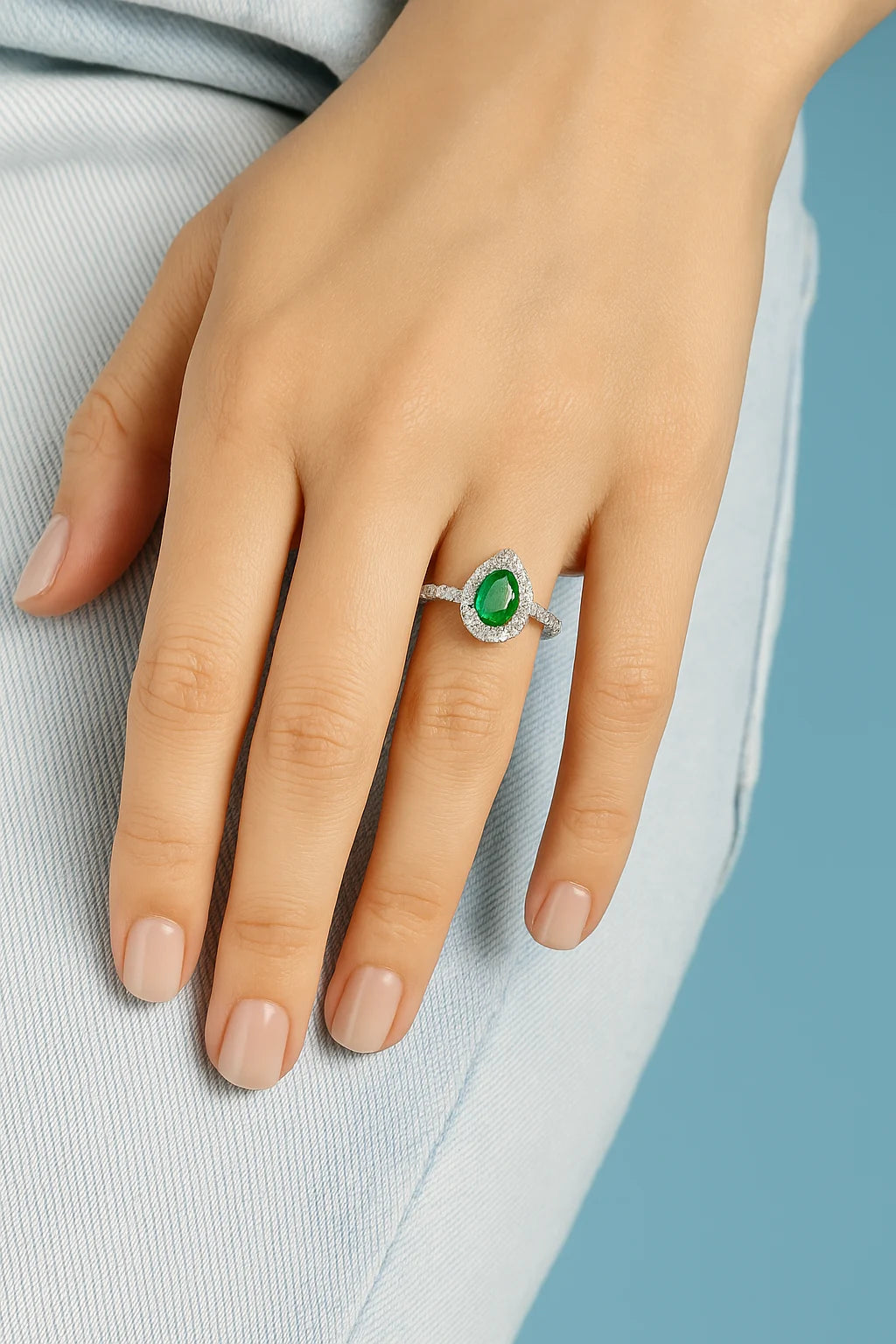Model wearing Cavell Drop of Passion natural emerald ring in sterling silver surrounded by round-cut cubic zirconia accents