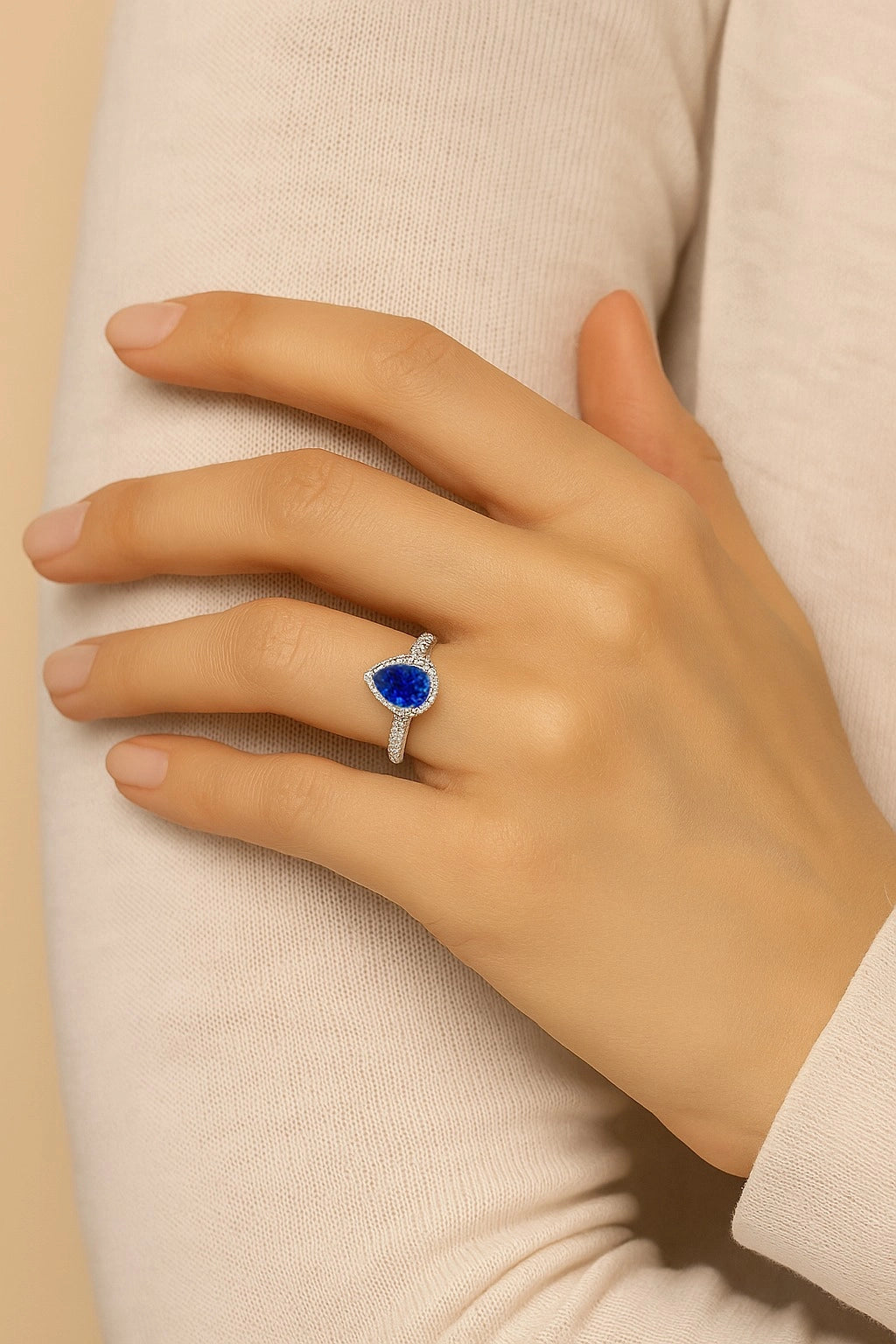 Model wearing Cavell Drop of Passion natural sapphire ring in sterling silver surrounded by round-cut cubic zirconia accents