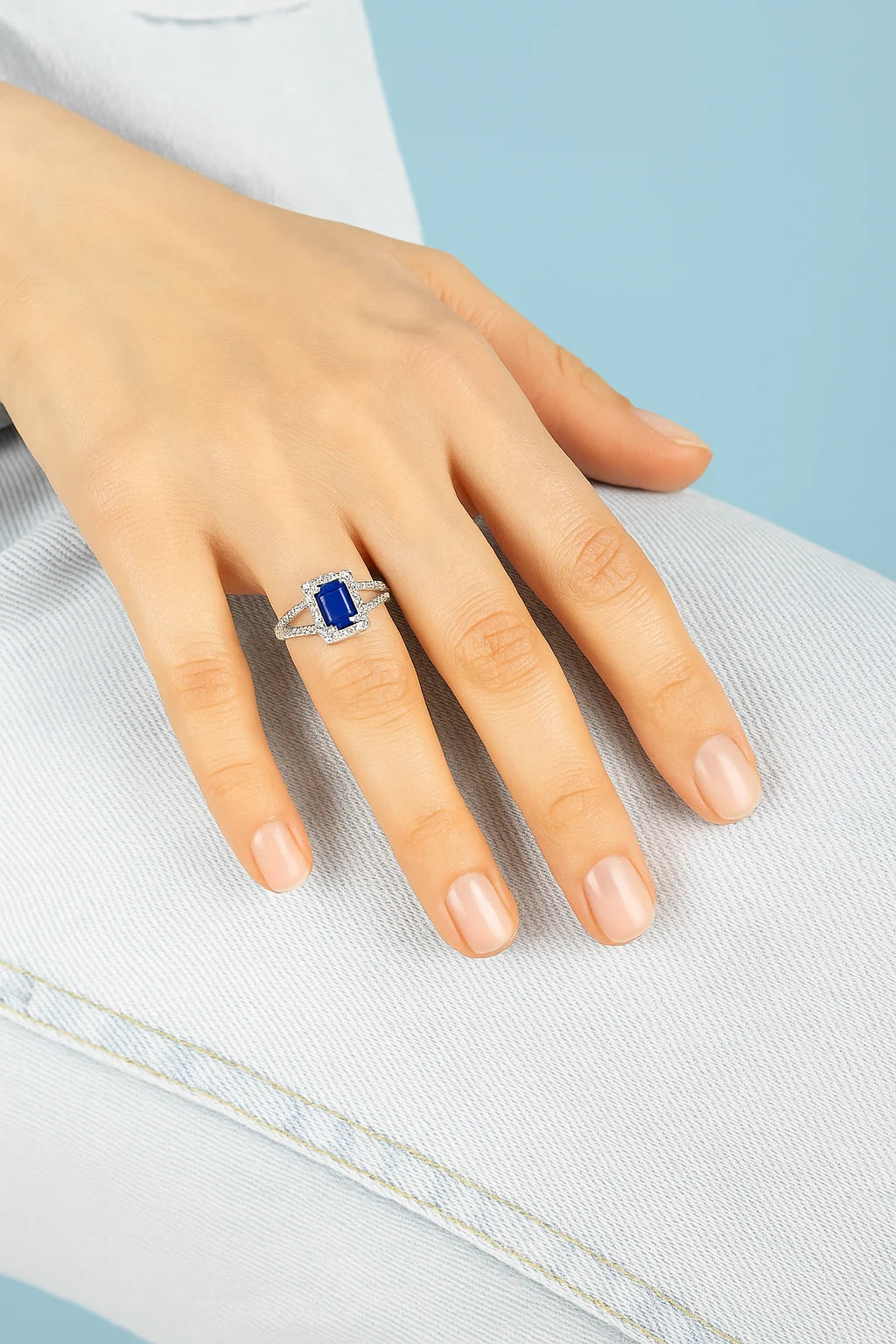 Model wearing Cavell Classic Allure natural sapphire ring in sterling silver surrounded by round-cut cubic zirconia accents