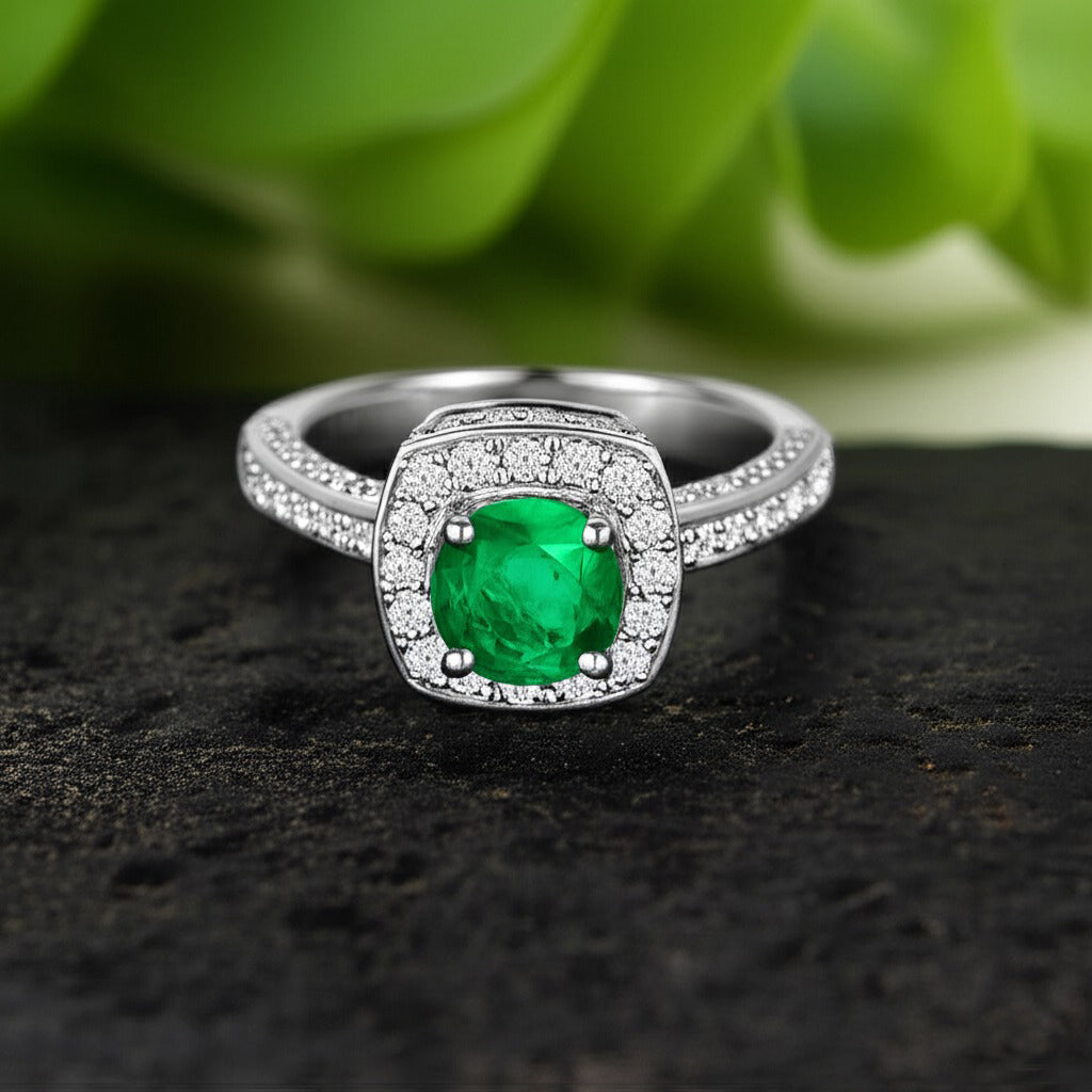 Cavell Everlasting Devotion natural emerald ring in sterling silver surrounded by round-cut cubic zirconia accents placed on a surface