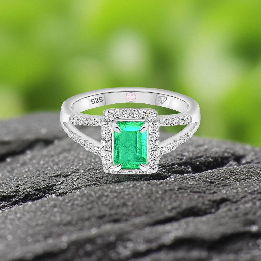 Cavell Classic Allure natural emerald ring in sterling silver surrounded by round-cut cubic zirconia accents placed on a surface