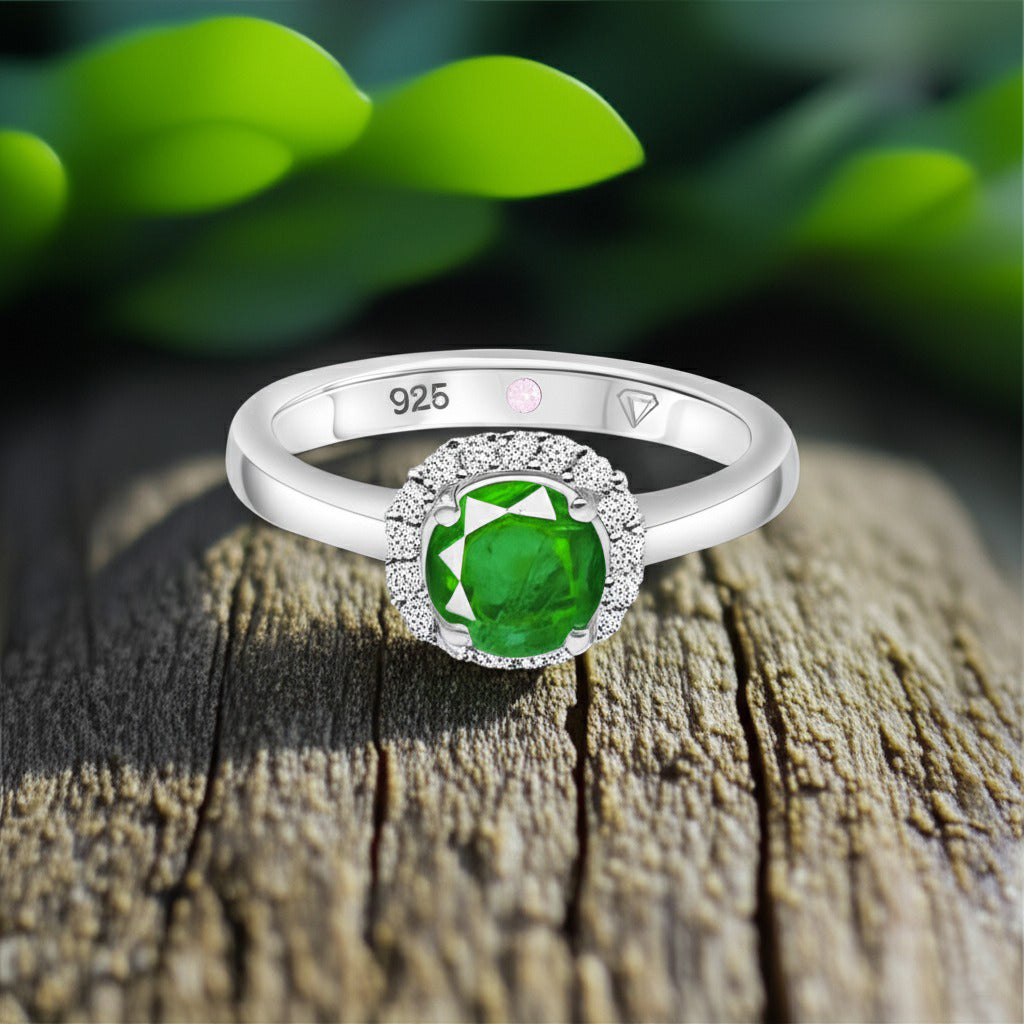 Cavell Eternal Love natural emerald ring in sterling silver surrounded by round-cut cubic zirconia accents placed on a surface