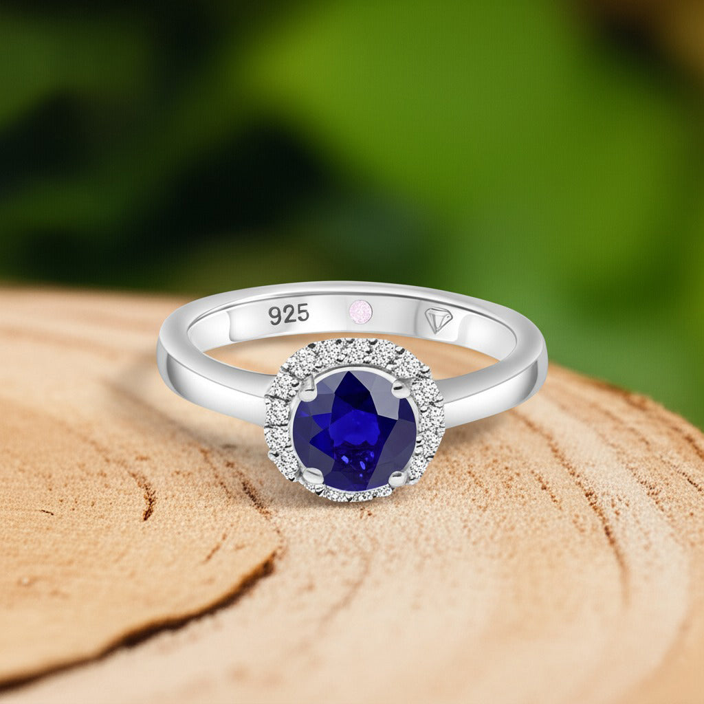 Cavell Eternal Love natural sapphire ring in sterling silver surrounded by round-cut cubic zirconia accents placed on a surface