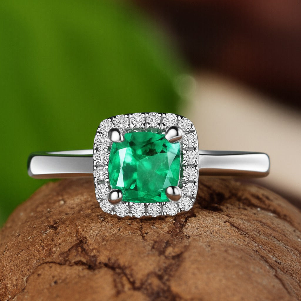 Cavell Touch of Luxury natural emerald ring in sterling silver surrounded by round-cut cubic zirconia accents placed on a surface