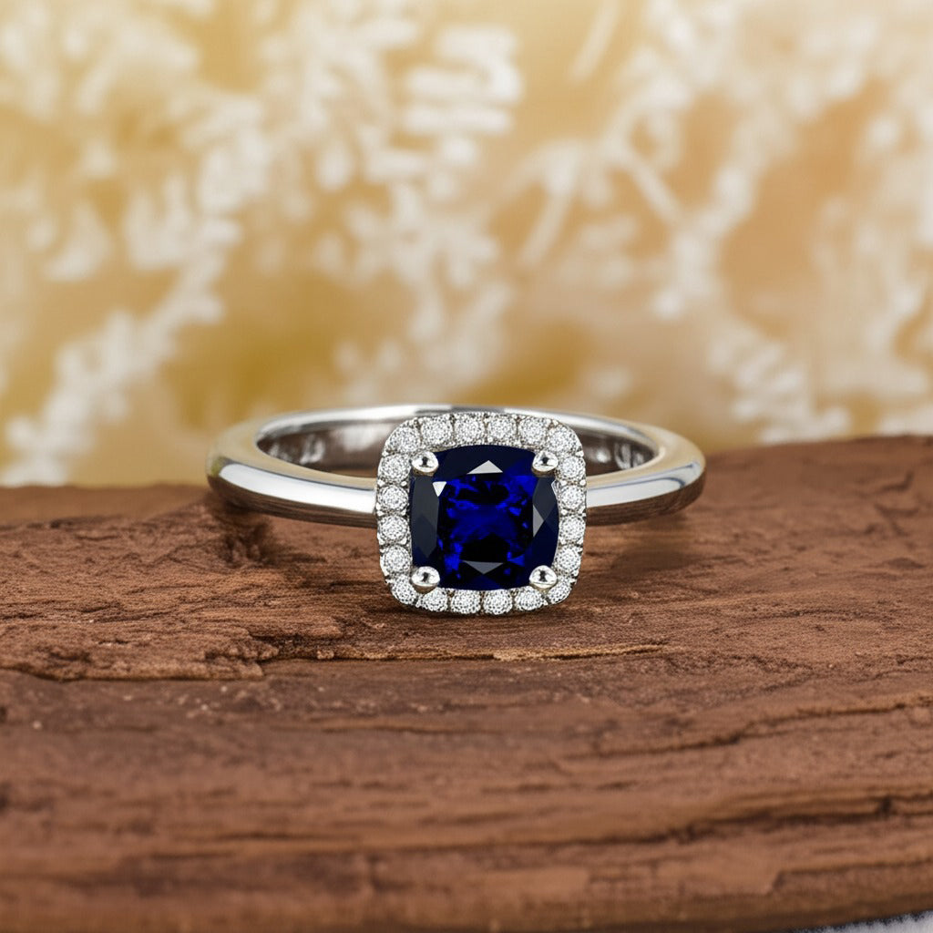 Cavell Touch of Luxury natural sapphire ring in sterling silver surrounded by round-cut cubic zirconia accents placed on a surface