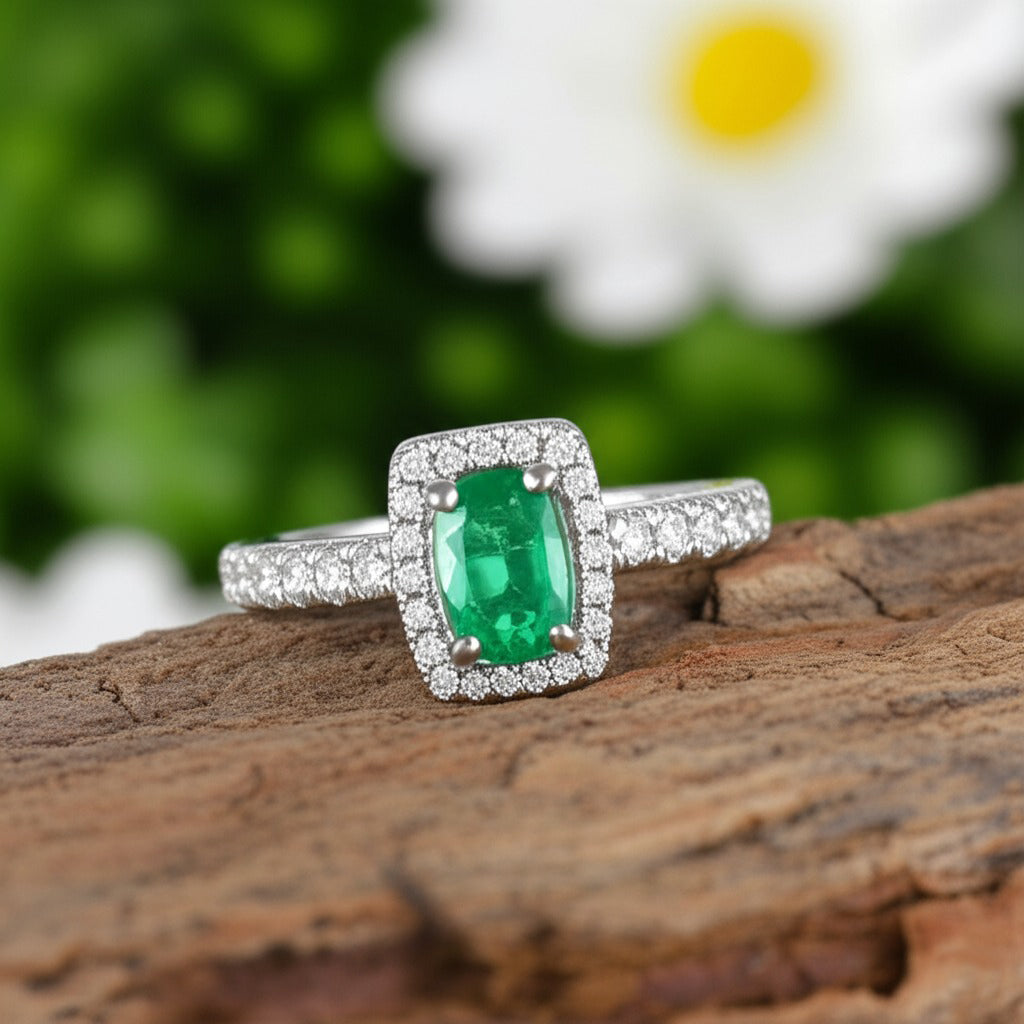 Cavell Feel Timeless natural emerald ring in sterling silver surrounded by round-cut cubic zirconia accents placed on a surface