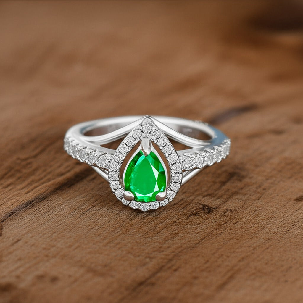 Cavell Tear Drop of Joy natural emerald ring in sterling silver surrounded by round-cut cubic zirconia accents placed in a surface