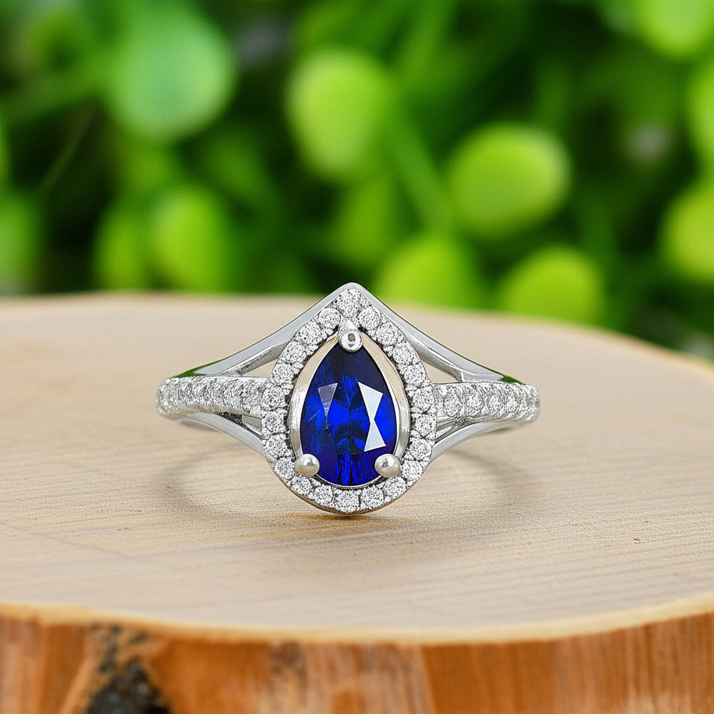 Cavell Tear Drop of Joy natural sapphire ring in sterling silver surrounded by round-cut cubic zirconia accents placed on a surface