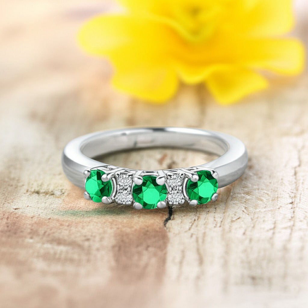 Cavell Trilogy of Loyalty natural emerald ring in sterling silver surrounded by round-cut cubic zirconia accents placed on a surface